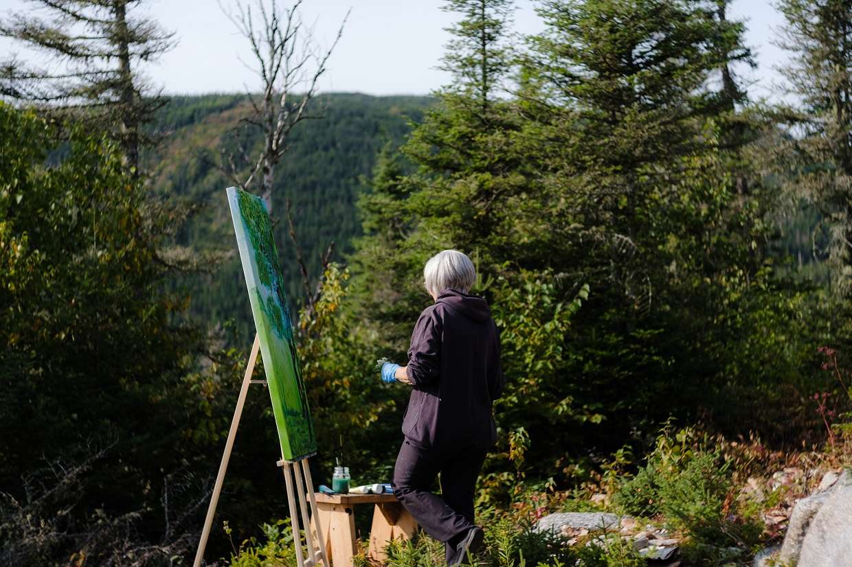 Une femme peint un tableau en haut de la montagne du Mont-Édouard.