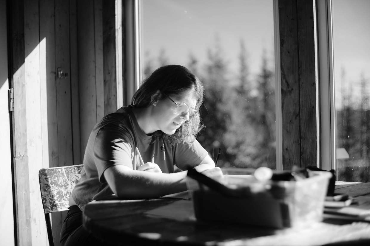 Une femme écrit sur une table près d'une fenêtre