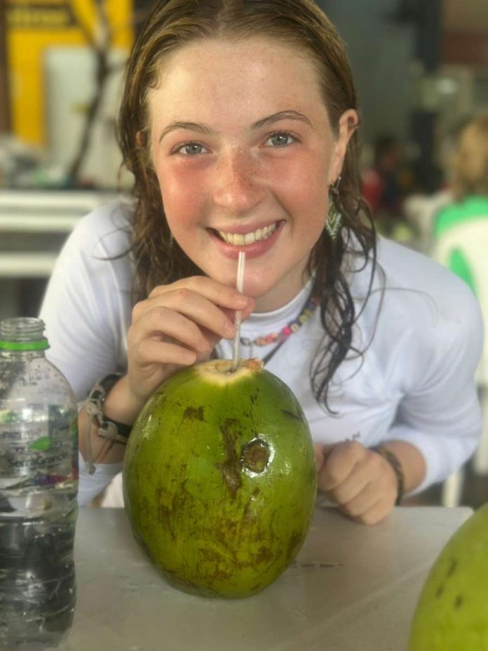 Une jeune fille boit à la paille directement dans une noix de coco
