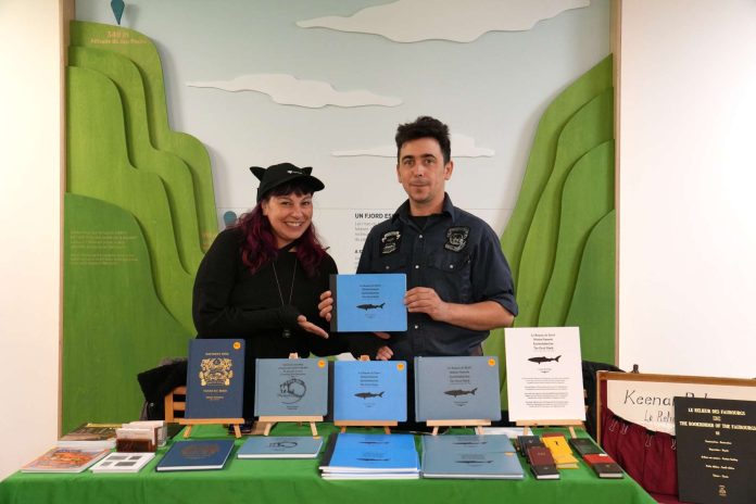 Deu xpersonne stiennent un stand dans un salon du livre