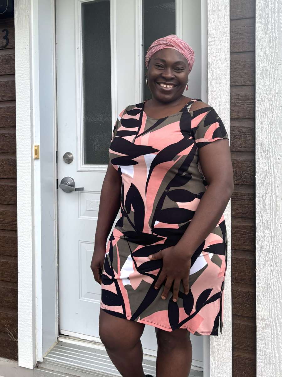 Une femme nore se tient devant une porte