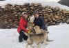 Un couple et un jeune chiot devant une corde de bois.