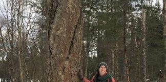Une femme acôté sur un gros bouleau jaune