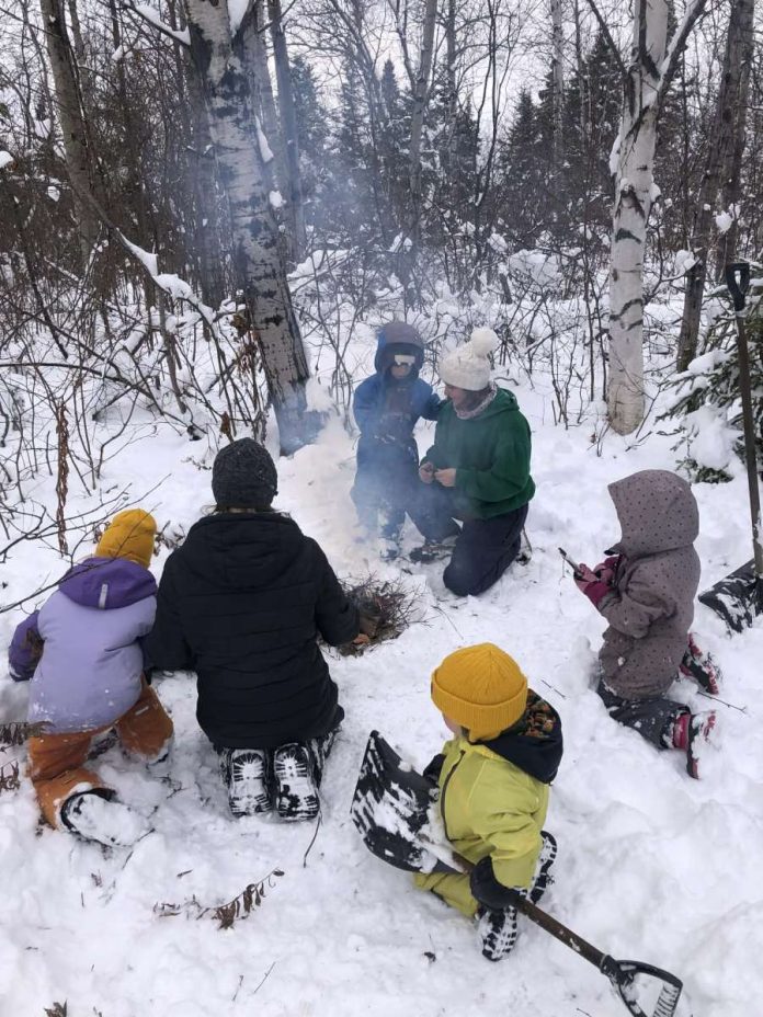De jeunes élèves d primare autour d'un feu de bois