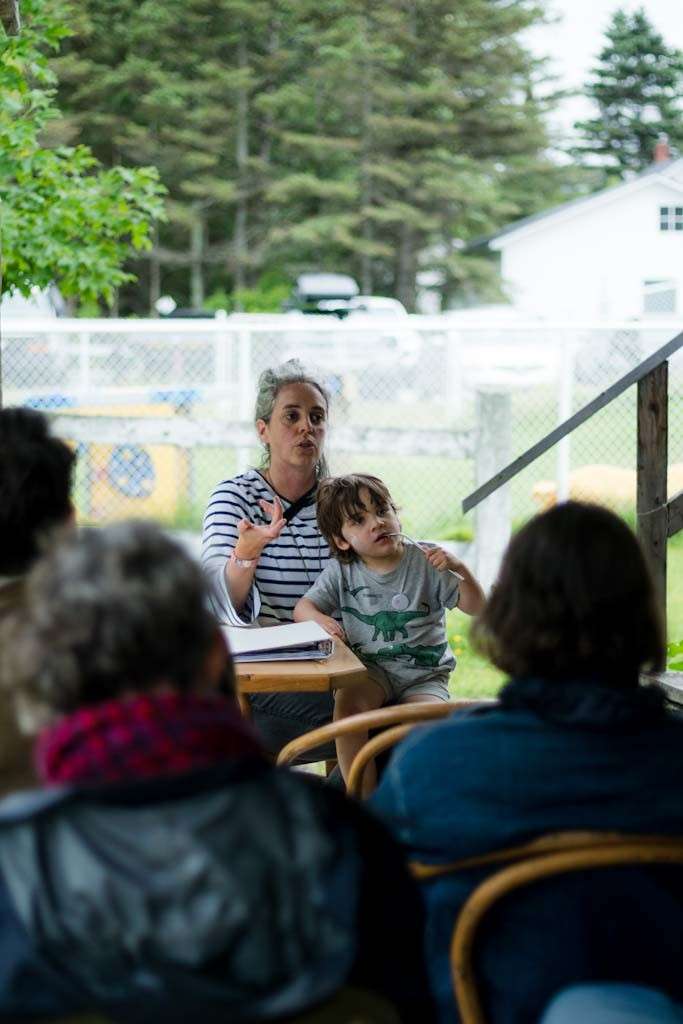 Une femme avec son enfant sur les genoux donne une conférence