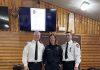 Trois pompiers posent dans un cahlet en bois rond