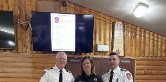 Trois pompiers posent dans un cahlet en bois rond