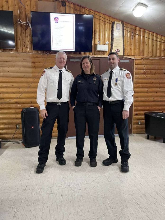 Trois pompiers posent dans un cahlet en bois rond
