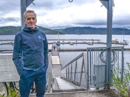 un homme pose les mains dans les poches devant la marina de L'Anse-Saint-Jean