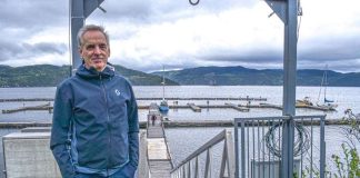un homme pose les mains dans les poches devant la marina de L'Anse-Saint-Jean